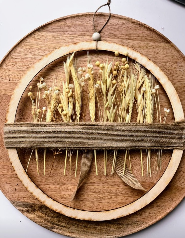 Naturalny wianek dekoracyjny boho z suszonych traw, drewna i juty, minimalistyczna dekoracja ścienna.