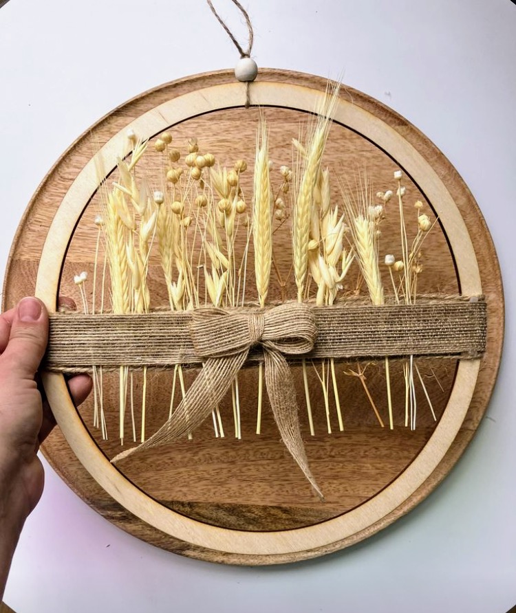 Ręcznie wykonany wianek boho z wysuszonych traw i zbóż na drewnianym kole z jutową wstążką.