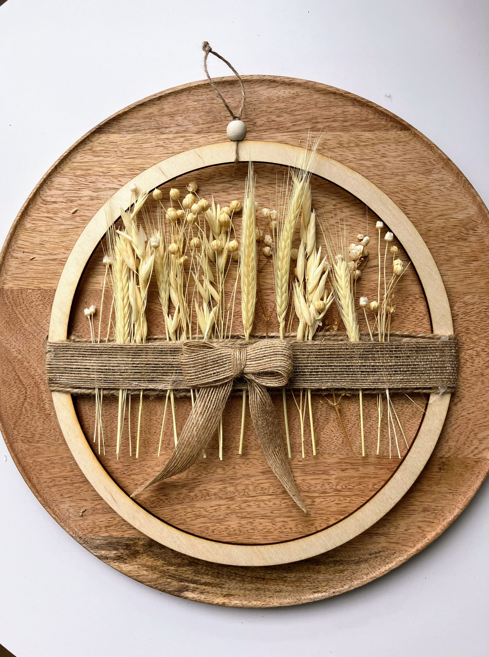 Ręcznie wykonany wianek boho z wysuszonych traw, zbóż i drewna, ozdobiony jutową wstążką – naturalna dekoracja ściany w stylu boho i slow life.