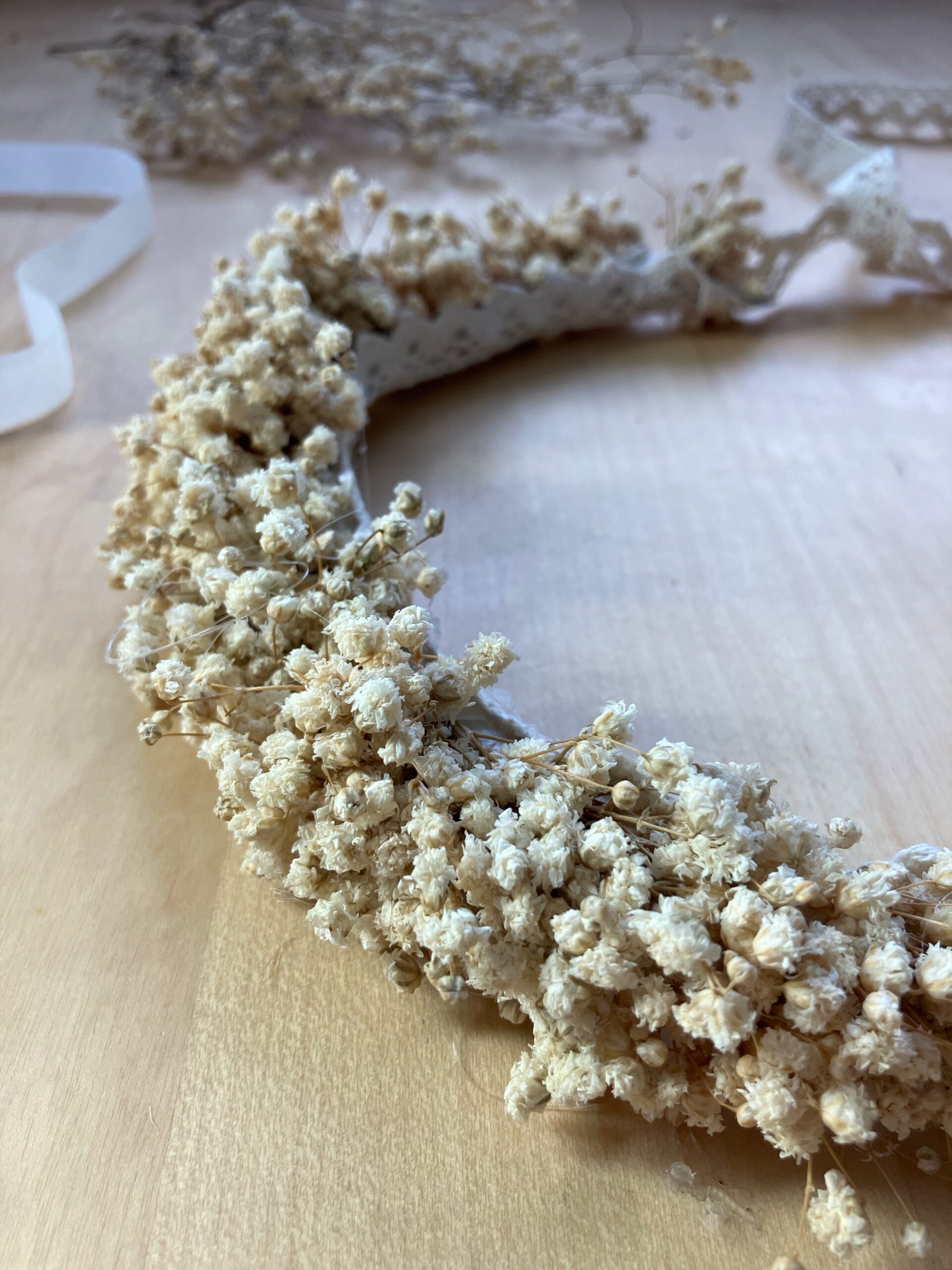 Beżowa korona kwiatowa z białej stabilizowanej gipsówki, minimalistyczny dodatek boho na ślub i sesję fotograficzną.