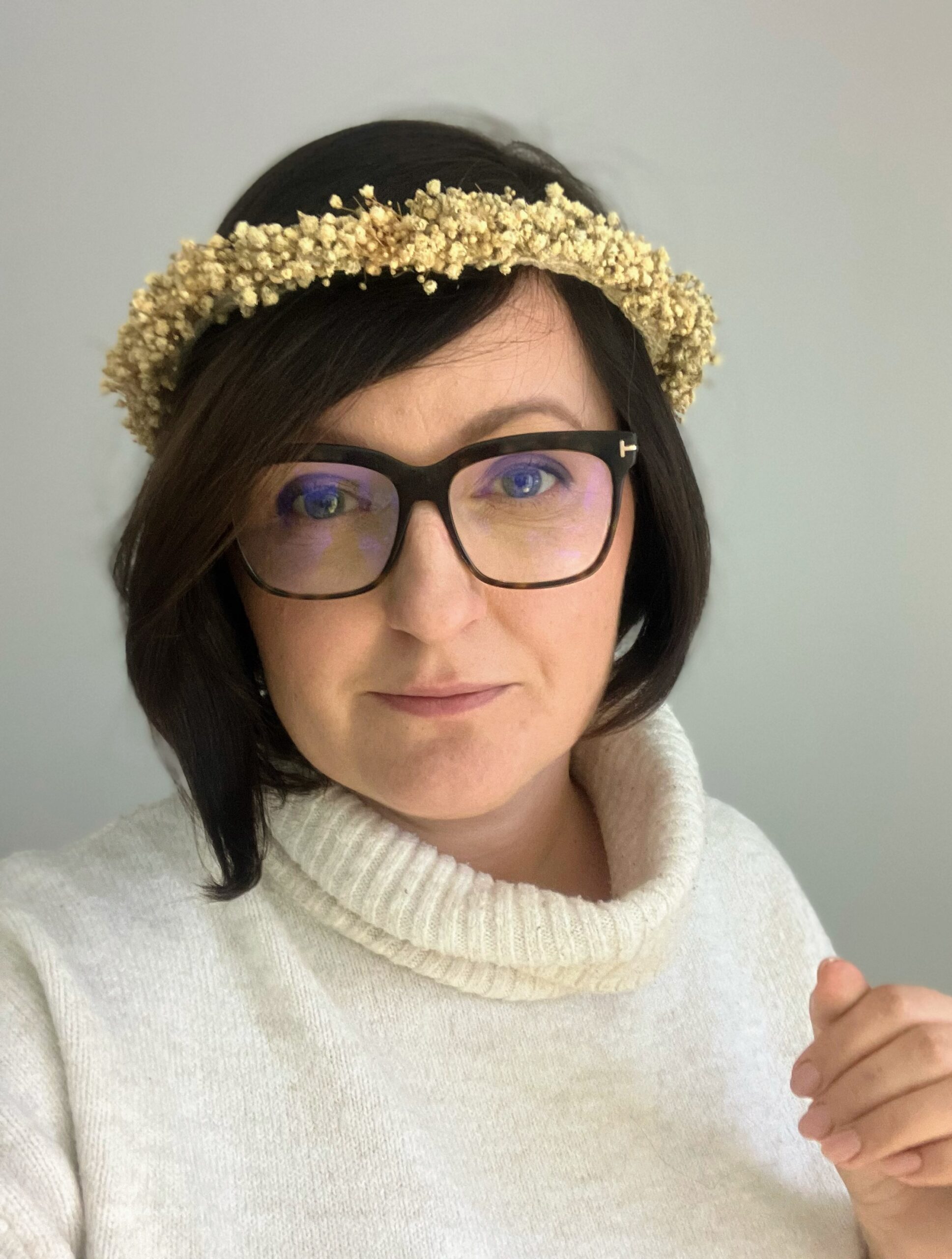 Modelka w delikatnym, beżowym wianku ze stabilizowanej gipsówki, patrząca w obiektyw